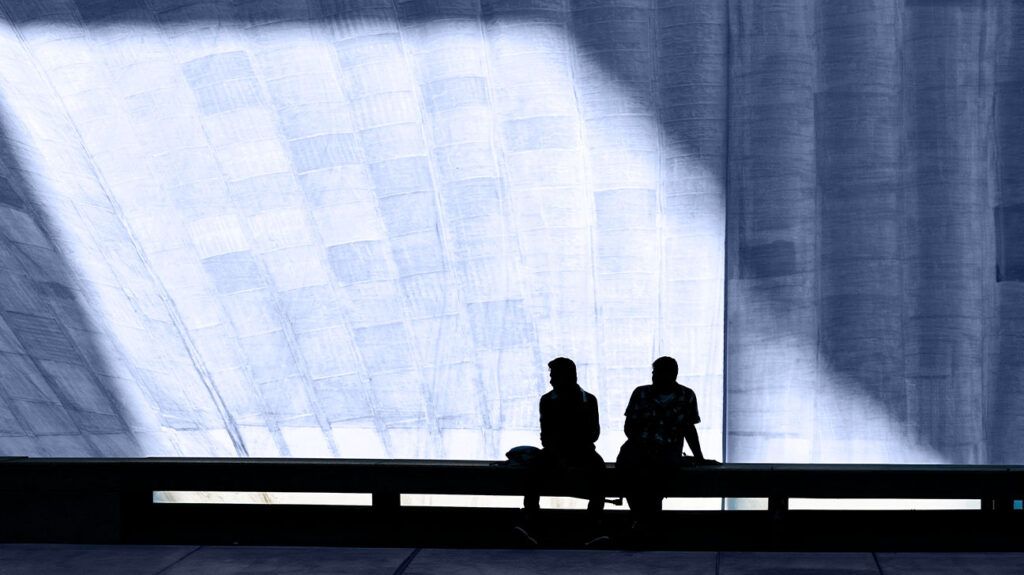 Silhouette of two people sitting on a bench
