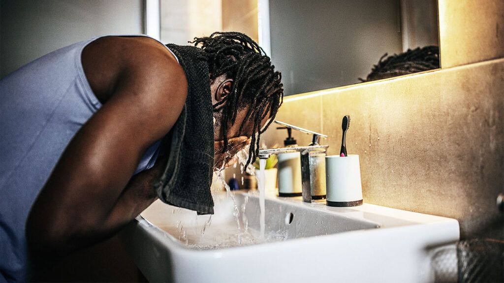 A person washing their face in a bathroom 1