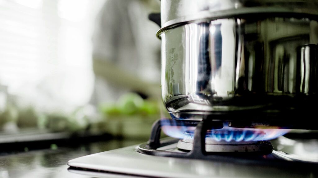 A metal steamer on a gas hob with blue flames, emitting VOCs.