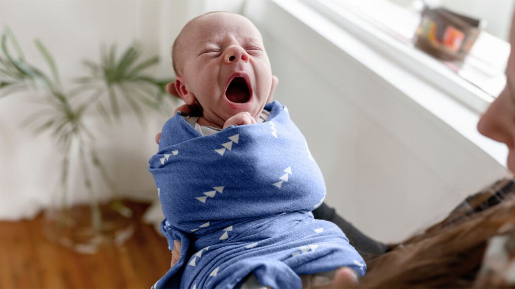 A parent swaddling a fussy baby to calm them. -2