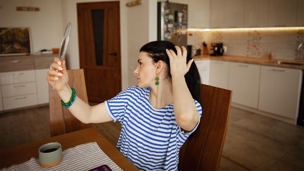 A woman checking her scalp for signs of seborrheic dermatitis or scalp psoriasis -1