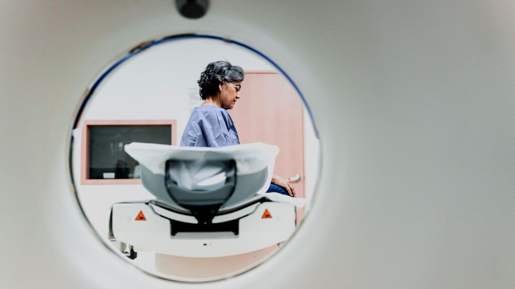 A woman sitting in CT machien getting ready for a scan