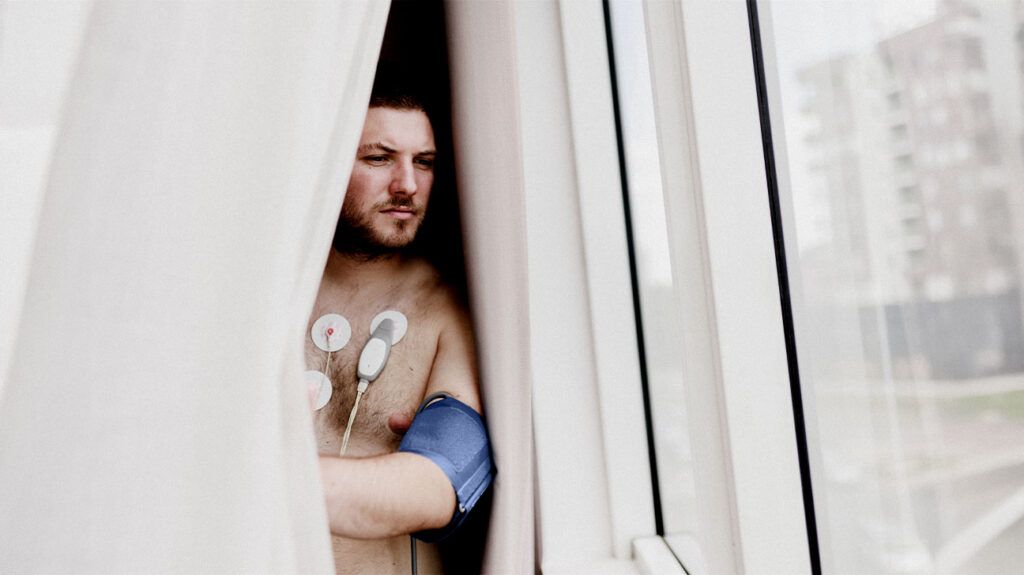A young man looks out a window while wearing a heart attack