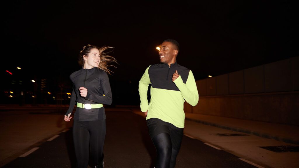A young man and woman jog at night