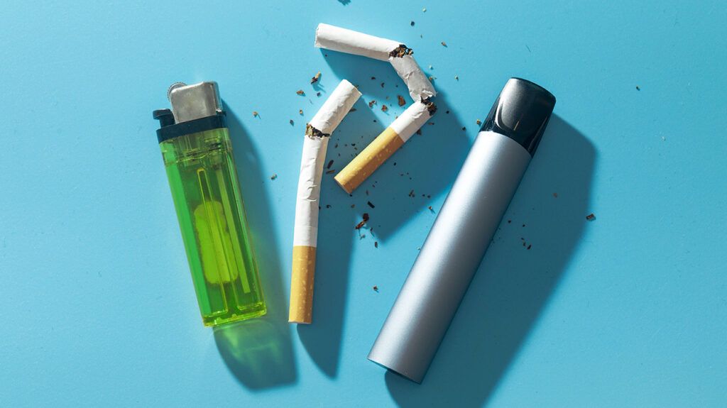 Broken cigarettes, a green lighter, and a vape against a light blue background