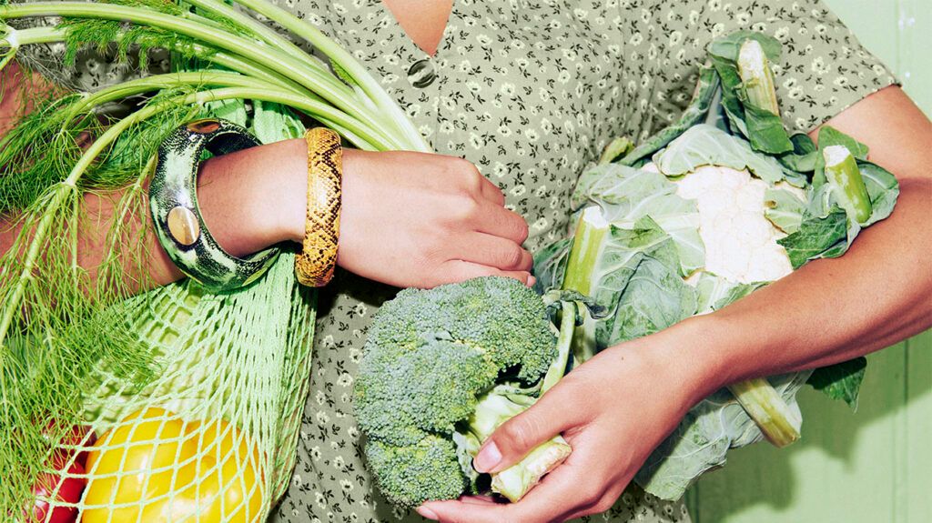 Person with an armful of green vegetables