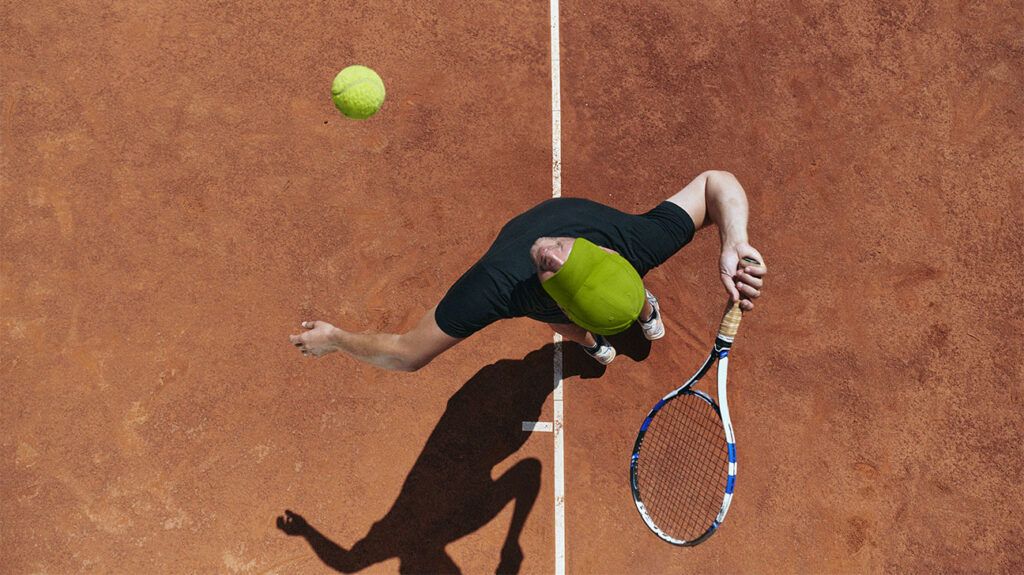 View from above a tennis player reaching to hit a ball