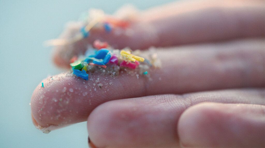 Close up of colorful microplastics on fingertips