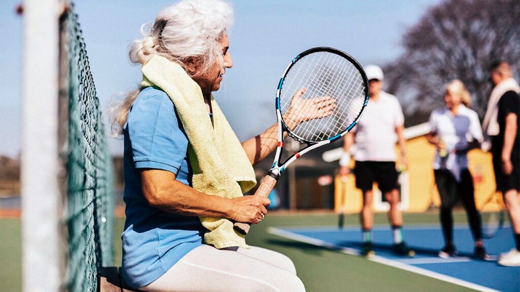 older person holding tennis racket