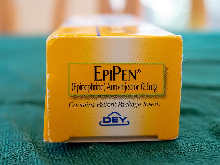 A yellow, EpiPen auto-injector pen box sits on top of a green towel.