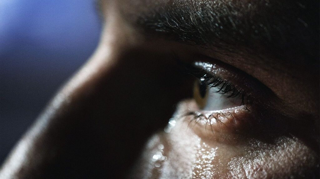 A close up of the eye and nose of a man sweating. -1