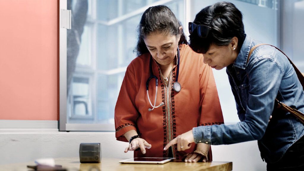 A female doctor looks at an iPad screen with a patient