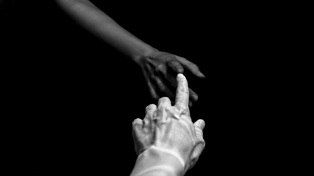 Black and white image of two people touching fingertips