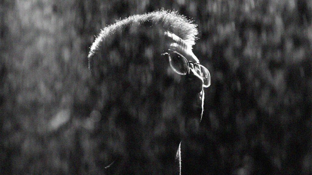 black and white photo of bespectacled person's head in the rain