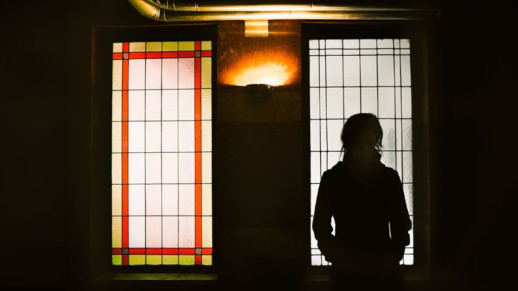Silhouette of a female in front of two large windows