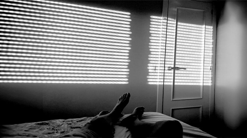 A person sleeps with the blinds closed in their bedroom