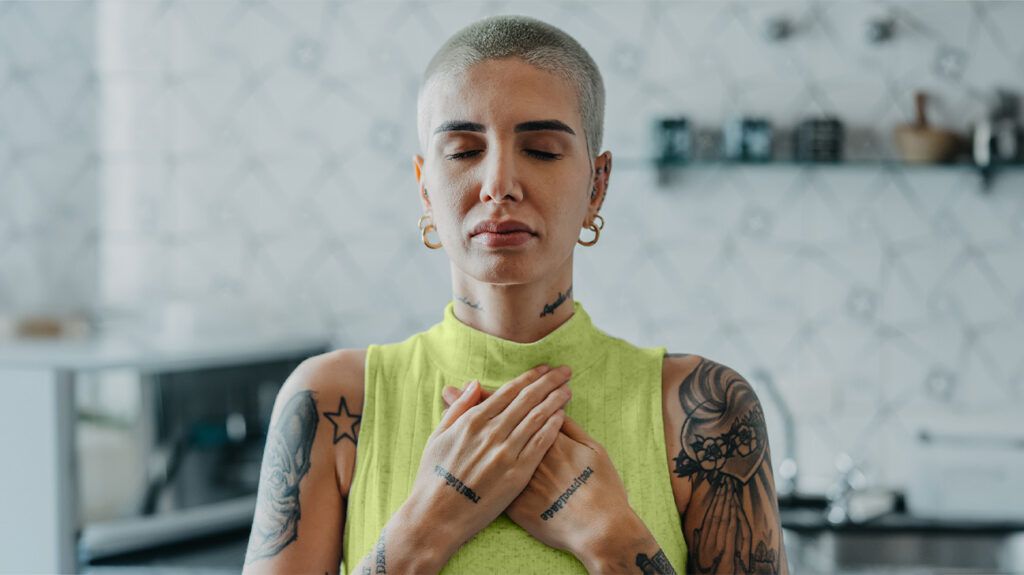 A woman closes her eyes and holds her chest while meditating