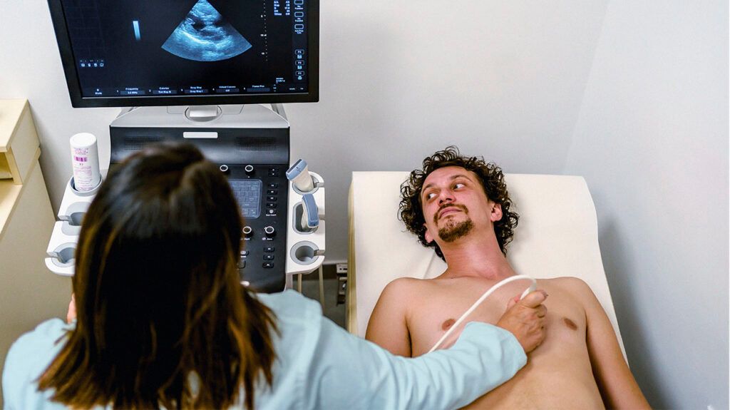 A technician performing an ultrasound scan on a man's chest to look for signs of cardiomyopathy.