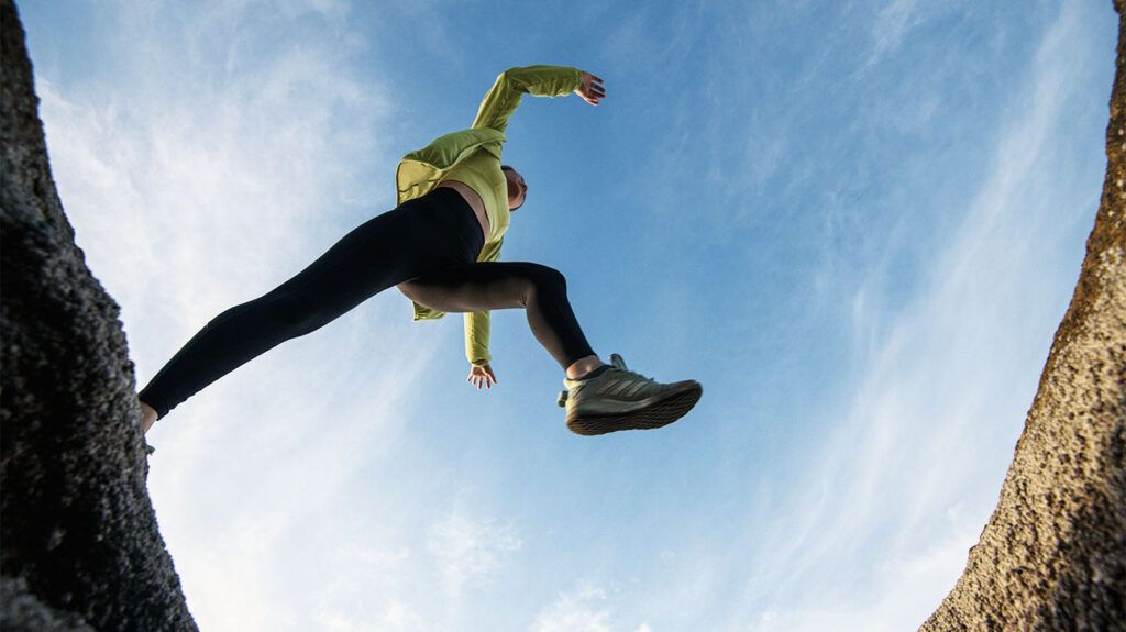 A person with hypermobility jumping over a rock, seen from below.