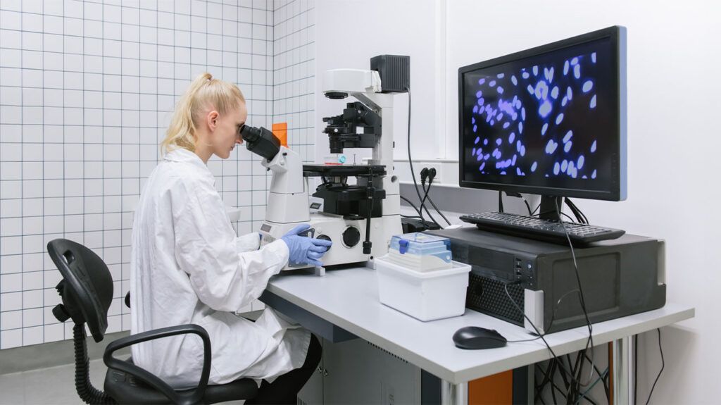 A female scientist peers into a microscope