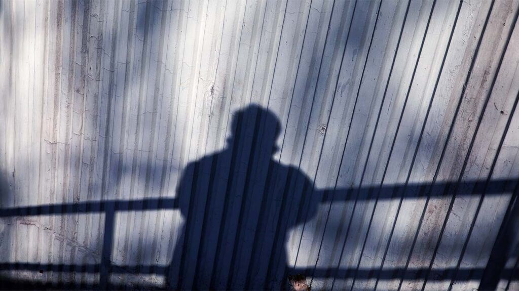 The shadow of a person leaning on a rail