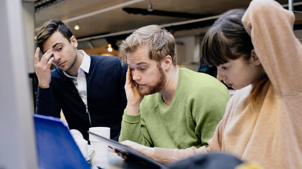 Three people working and looking stressed or anxious