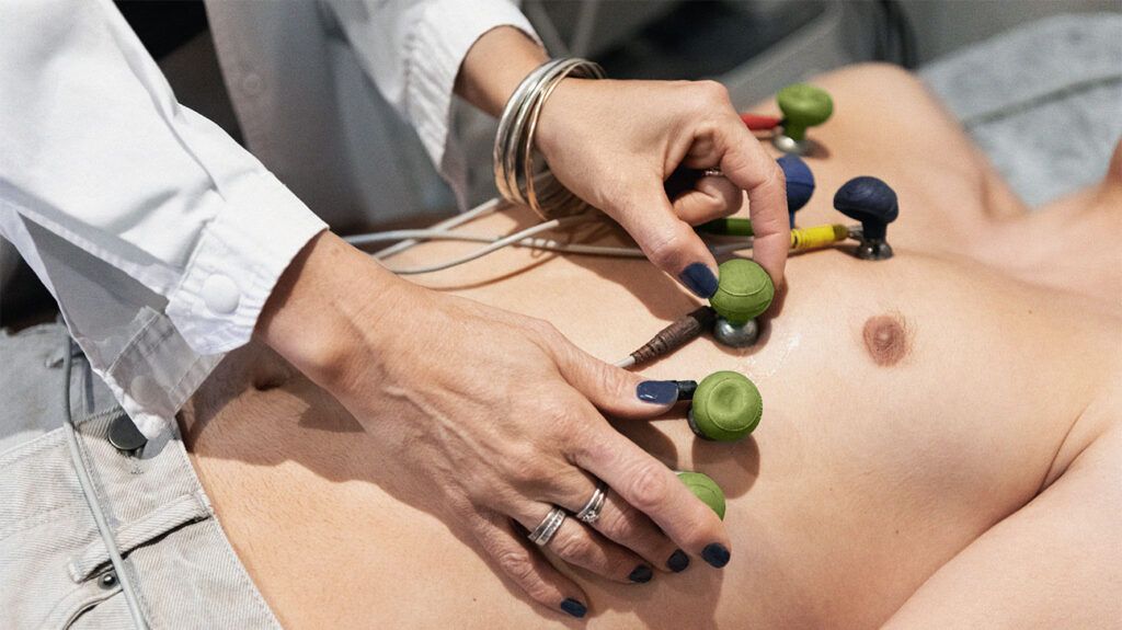 Cardiologist placing electrodes on a young patient's chest while performing an electrocardiogram for structural heart disease.