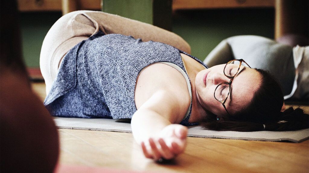 Female in a yoga class, laying on the floor stretching