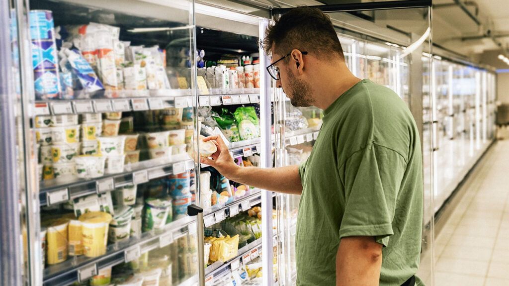 A person is looking at food in a fridge in a store.