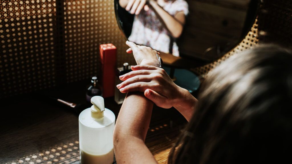 A girl rubs skin lotion on her arm