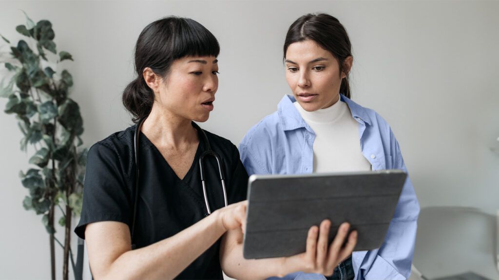 A doctor is showing a patient something on a tablet screen.