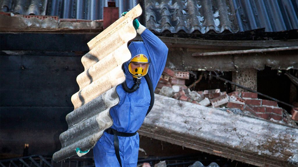 A person removing asbestos from a building site wearing full protective gear to protect themselves from epithelioid mesothelioma.-2