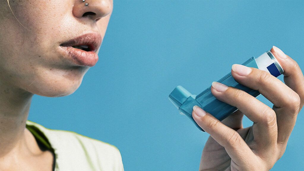 A person holding an inhaler near their mouth 1