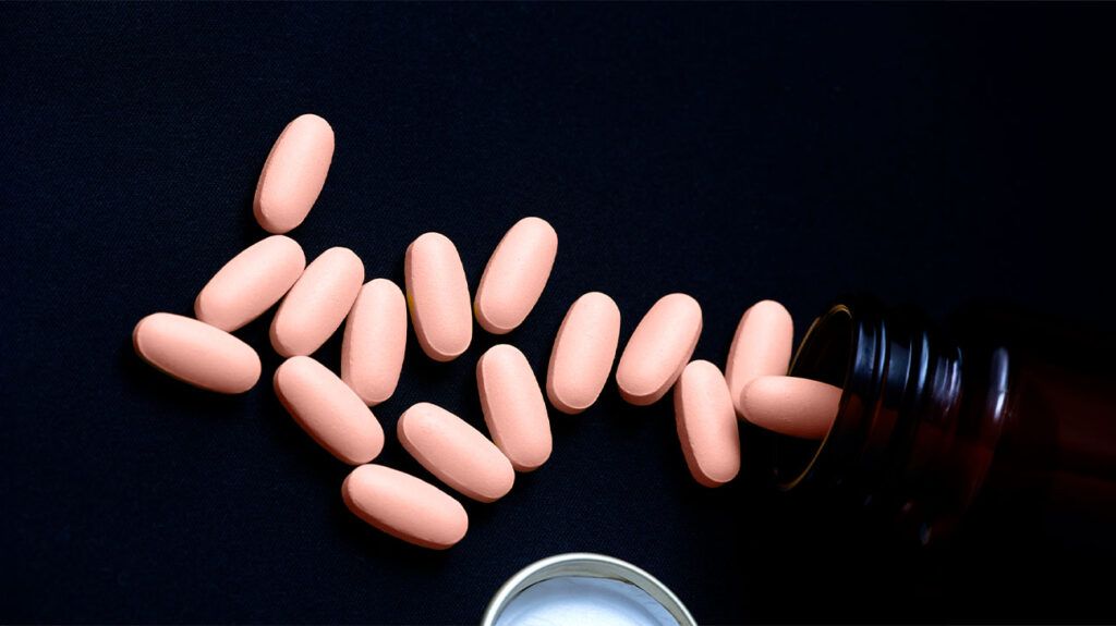 Statin pills emptied from bottle on black background