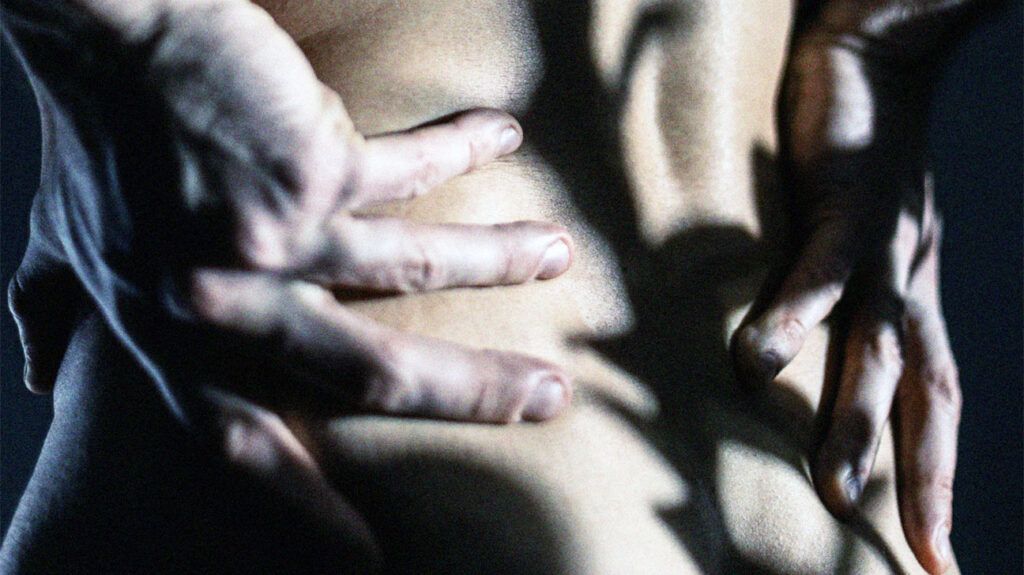 Close up of a person's hands rubbing their lower back