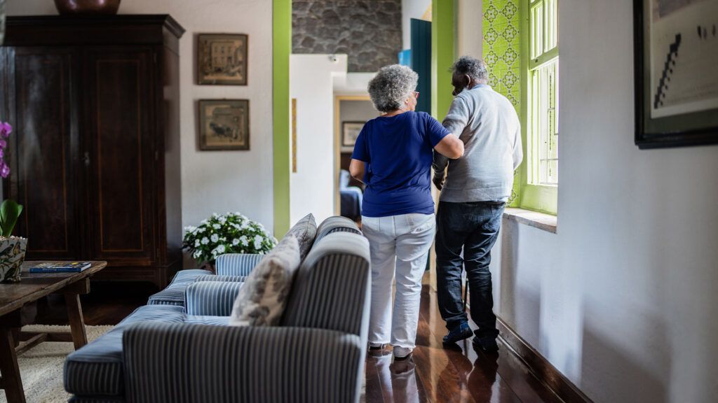 older couple walking through a living-room, seen from the back