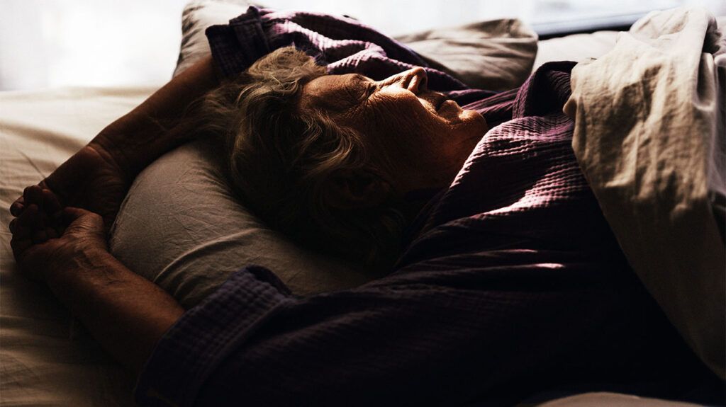 A woman who may have peripheral artery disease sleeping on her side in bed.-3