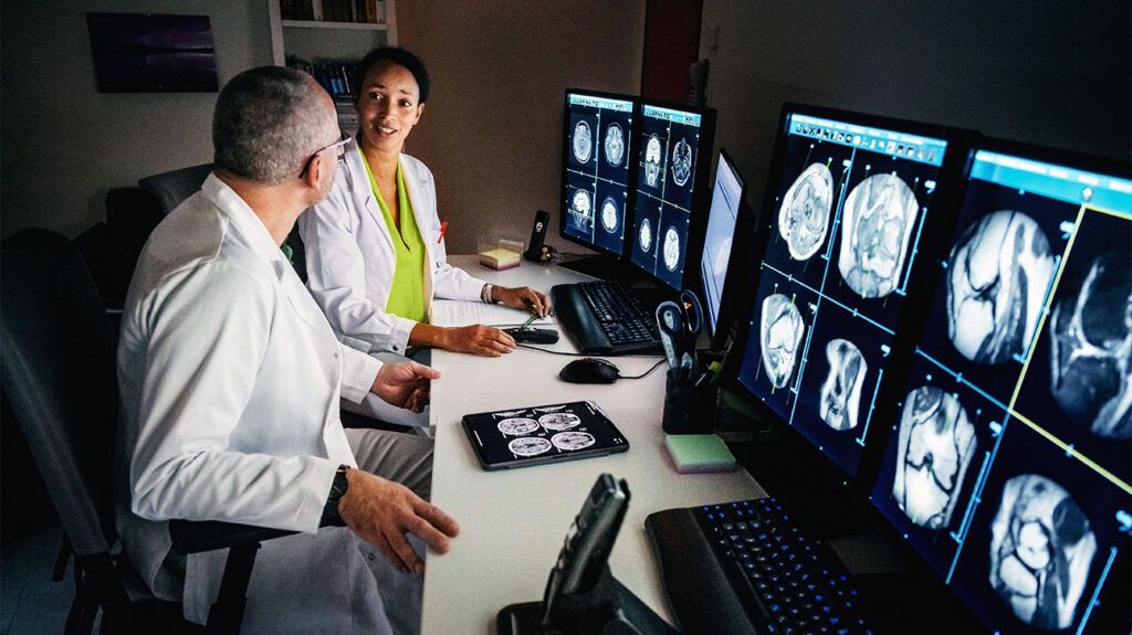 Healthcare professionals looking at scans on computer screens