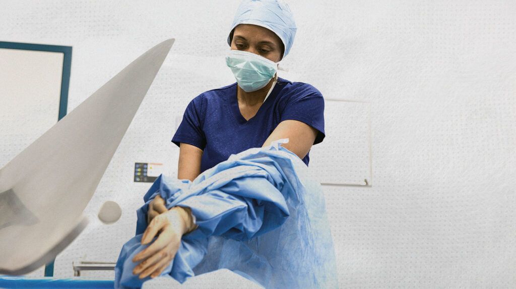 A surgeon is removing their gown after a procedure.