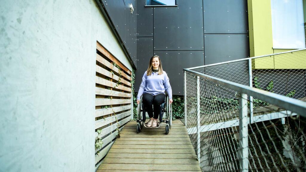 A woman using a wheelchair to go down a ramp in a modern building.