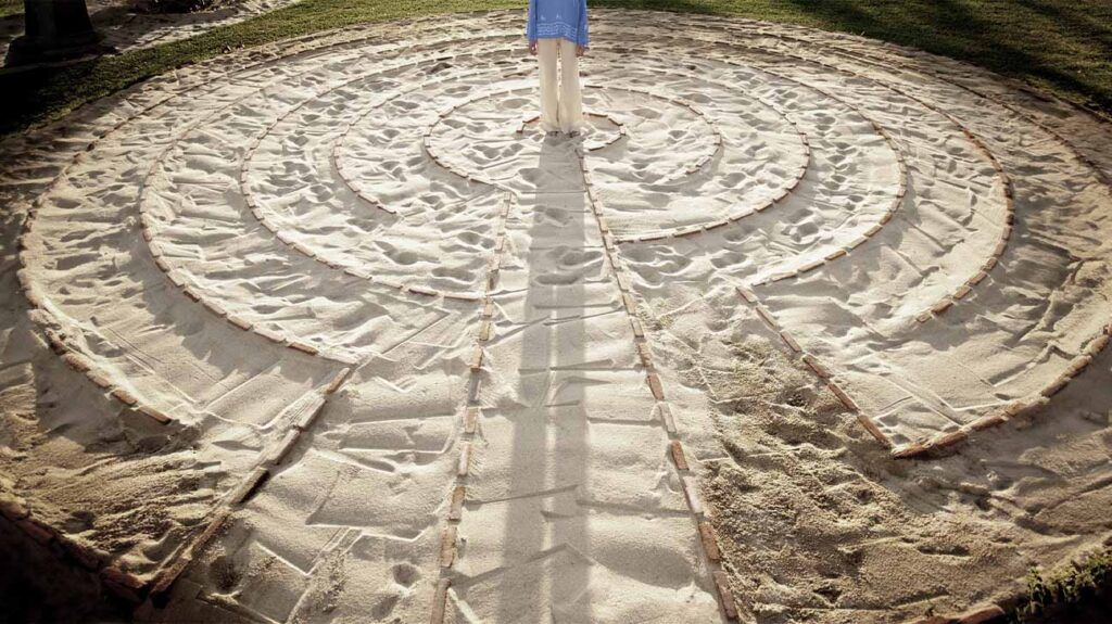 Person standing in the middle of a sand labyrinth