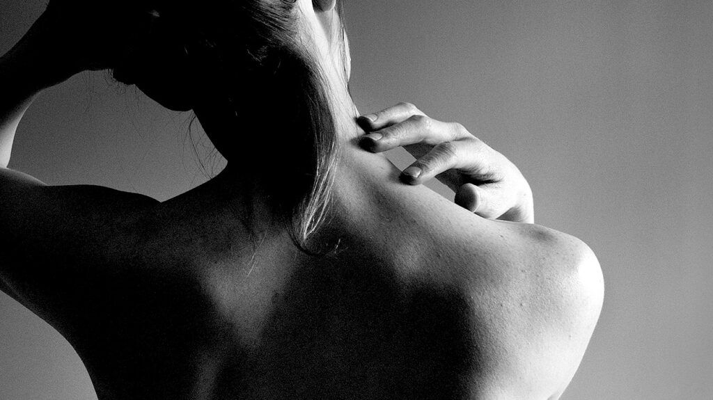 Closeup of a person scratching their neck.