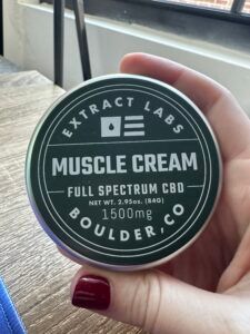 extract labs cbd muscle relief cream in a tin being held by hand