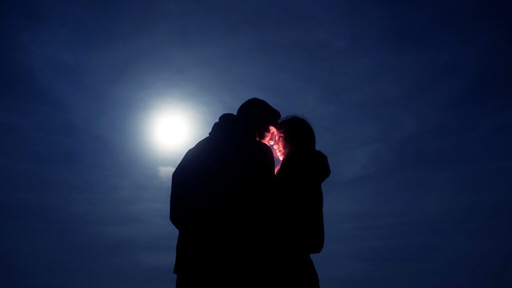 Silhouette of a couple against the moon