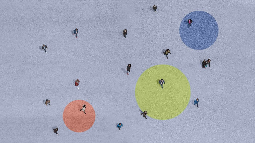 Aerial shot of people walking over grey concrete with a red, yellow, and blue circle painted on the ground.