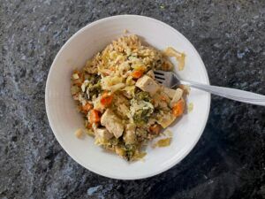 Bowl of Modify Health rice and vegetable meal on counter top with fork.