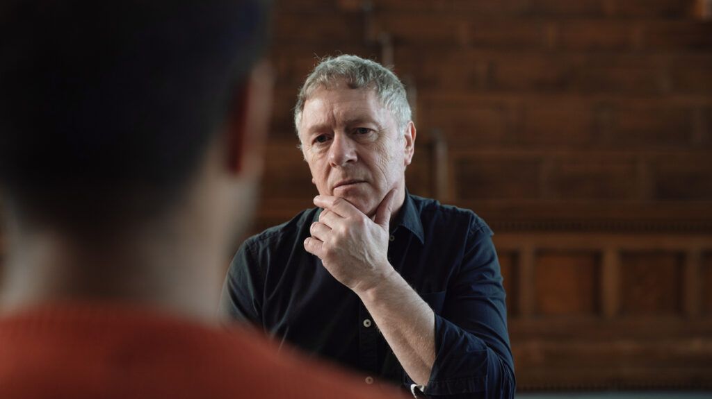A therapist stroking his chin and listening to a client.