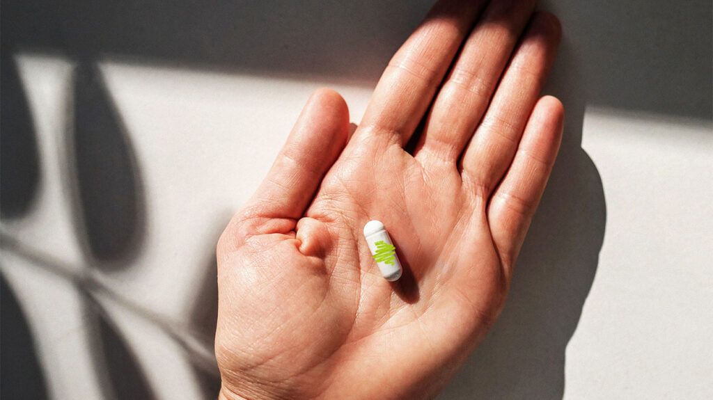 A person's hand holding a vitamin B6 capsule