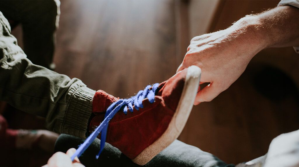 An adult tying a child's shoelaces. -3