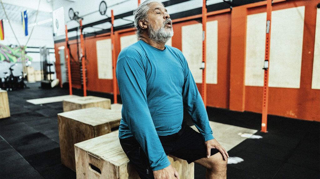 A man sitting down to rest in a gym locker room.